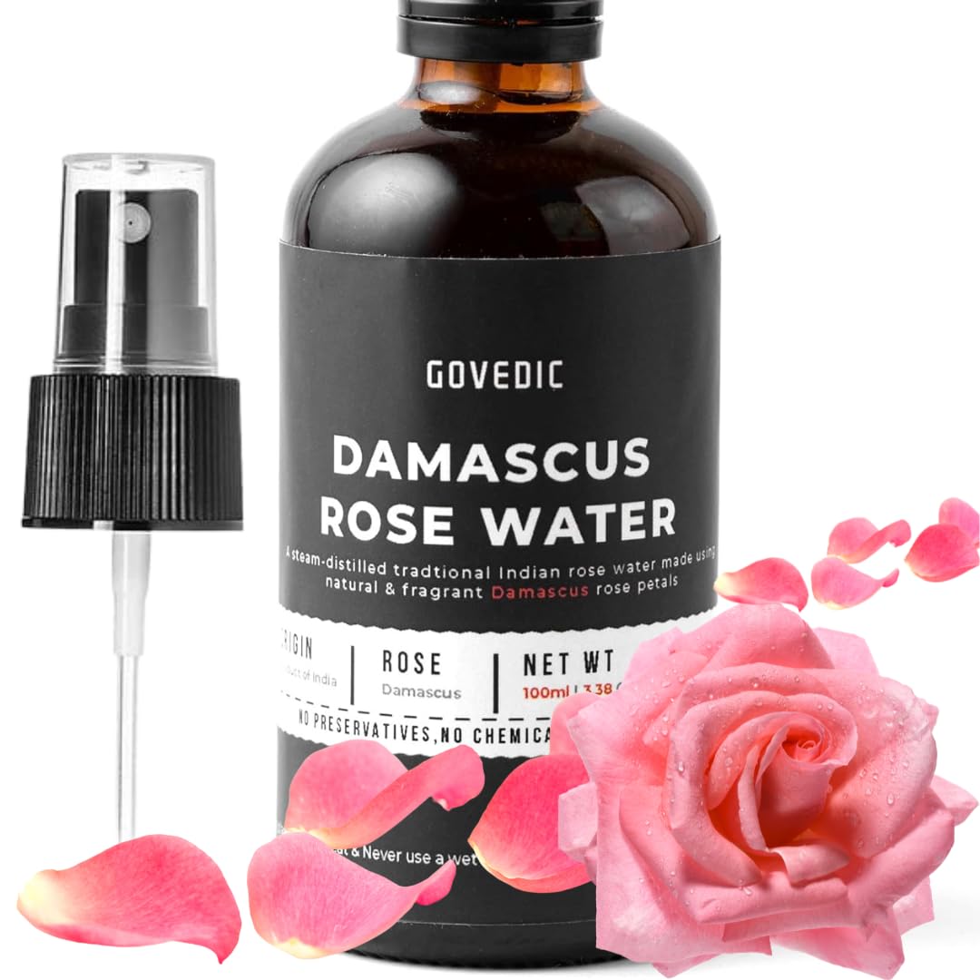Bottle of Govedic Damascus Rose Water with a spray nozzle and pink rose petals on a white background