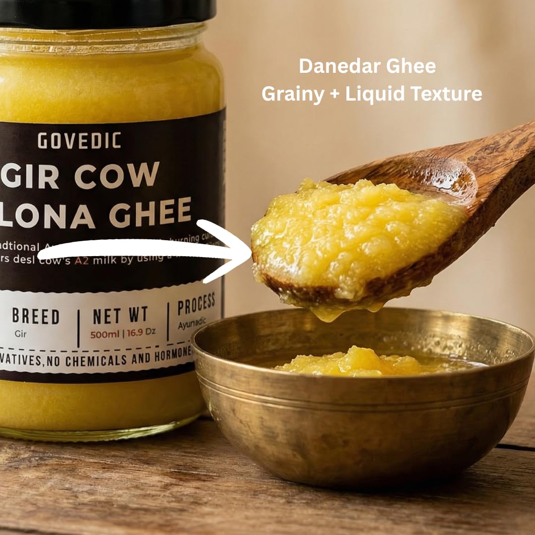 Jar of Govedic Gir Cow Gola Ghee with a wooden spoon and bowl showing its grainy and liquid texture.