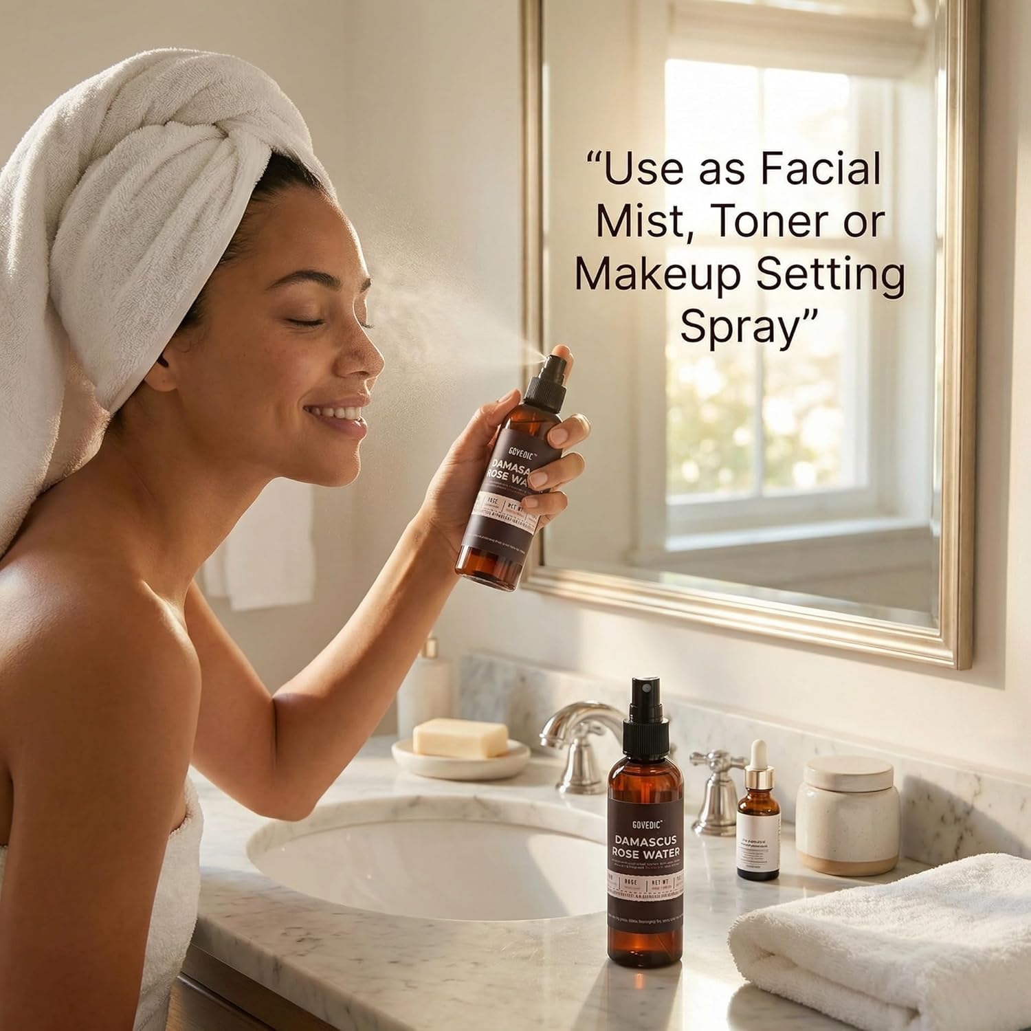 Woman using a facial mist spray in a bathroom setting with product bottles on the counter.